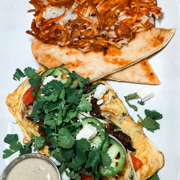 Pelican Restaurant's omelet with cilantro, jalapenos, and feta, served with hash browns and flatbread.